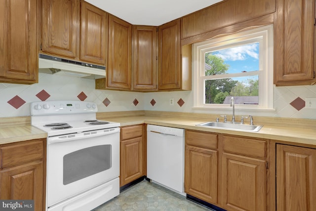 kitchen featuring decorative backsplash, a sink, light countertops, under cabinet range hood, and white appliances