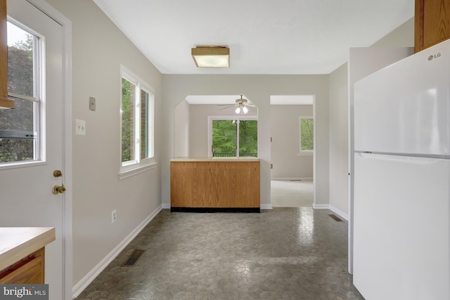 kitchen featuring a healthy amount of sunlight, freestanding refrigerator, a ceiling fan, and visible vents