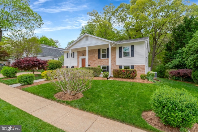 bi-level home with brick siding and a front yard