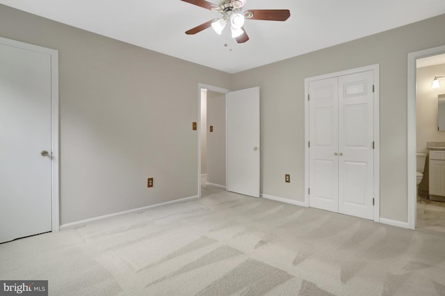 unfurnished bedroom featuring baseboards, ensuite bathroom, and light colored carpet