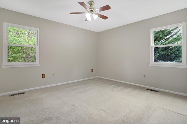 unfurnished room with visible vents, baseboards, a wealth of natural light, and light carpet