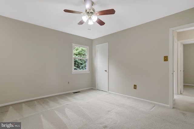 spare room with baseboards, ceiling fan, and light carpet
