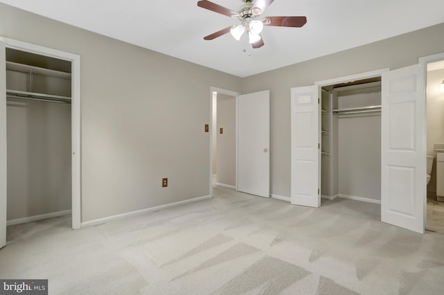 unfurnished bedroom featuring two closets, baseboards, and light carpet
