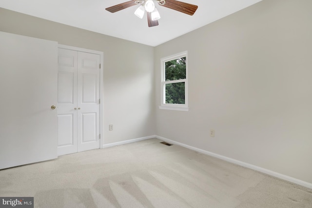 unfurnished bedroom with a ceiling fan, visible vents, light colored carpet, baseboards, and a closet