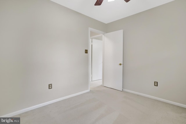 spare room with baseboards, a ceiling fan, and light colored carpet