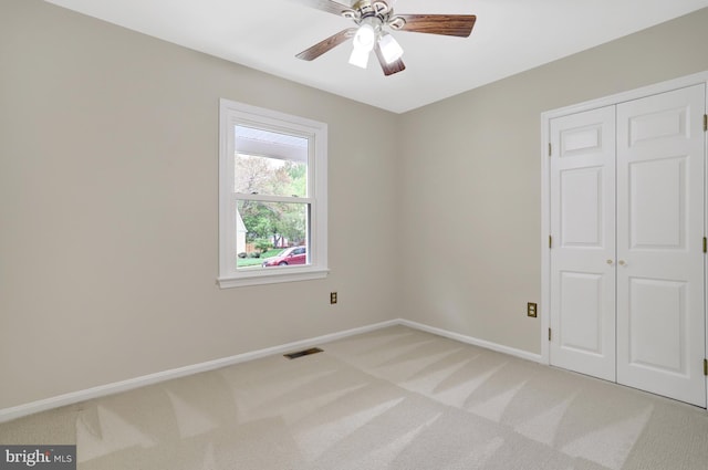 spare room with a ceiling fan, baseboards, visible vents, and light carpet