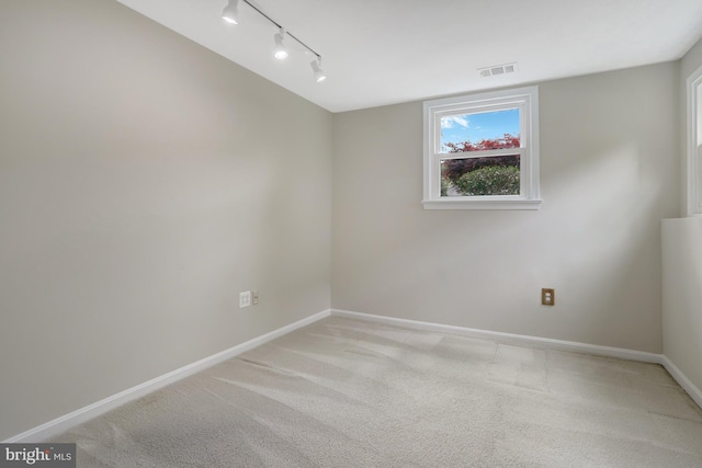 unfurnished room with baseboards, visible vents, track lighting, and light carpet