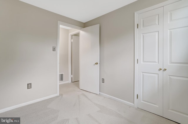 unfurnished bedroom featuring baseboards, visible vents, carpet, and a closet