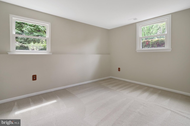 carpeted spare room with baseboards, visible vents, and a wealth of natural light