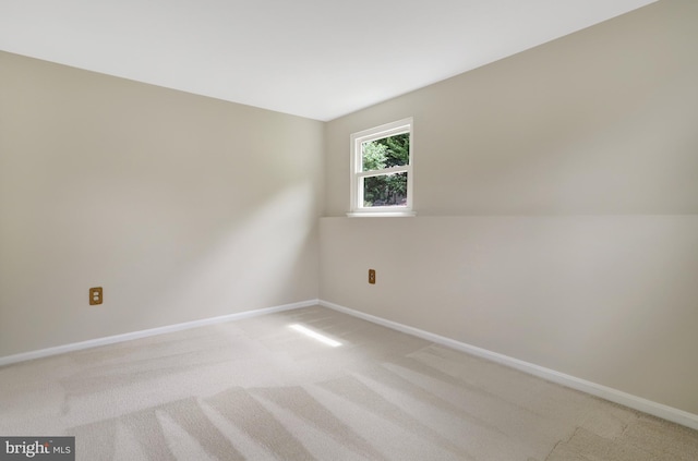empty room featuring baseboards and light carpet