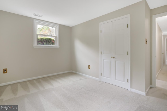 unfurnished bedroom with light colored carpet, baseboards, visible vents, and a closet