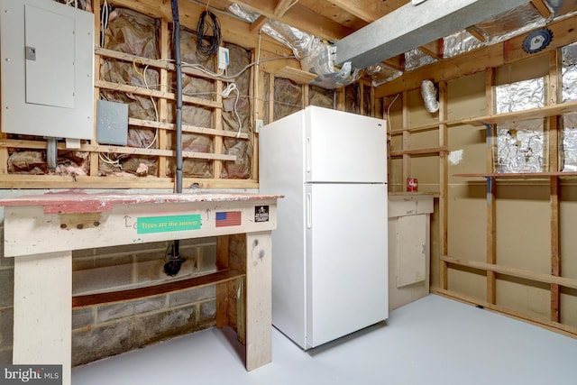 unfinished basement featuring freestanding refrigerator and electric panel