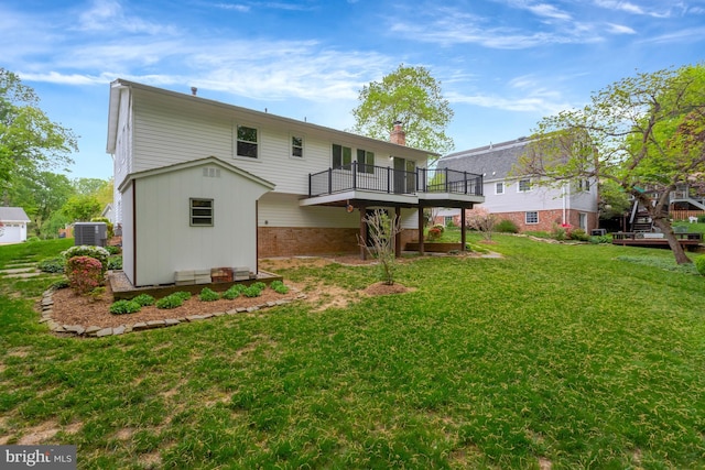 rear view of property featuring a chimney, a lawn, a wooden deck, brick siding, and central AC