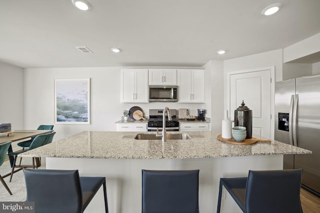 111 Yurok Ct, Winchester, VA 22602 - kitchen featuring light stone counters, appliances with stainless steel finishes, a kitchen breakfast bar, and white cabinetry