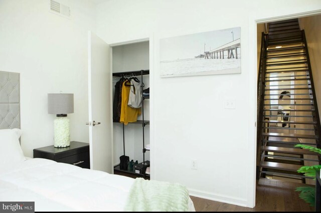 bedroom featuring wood finished floors, visible vents, a walk in closet, a closet, and baseboards