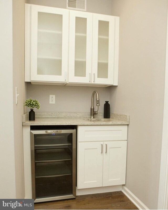 bar featuring dark wood finished floors, wine cooler, wet bar, visible vents, and a sink