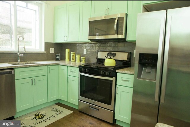 kitchen with tasteful backsplash, appliances with stainless steel finishes, dark wood-style floors, and a sink