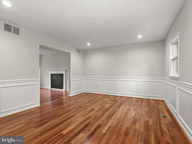 3826 Perryhurst, Nottingham, MD 21236 - unfurnished room with wood finished floors, recessed lighting, a decorative wall, wainscoting, and a fireplace