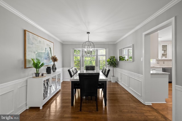 dining room featuring crown molding, a wainscoted wall, a decorative wall, and a chandelier