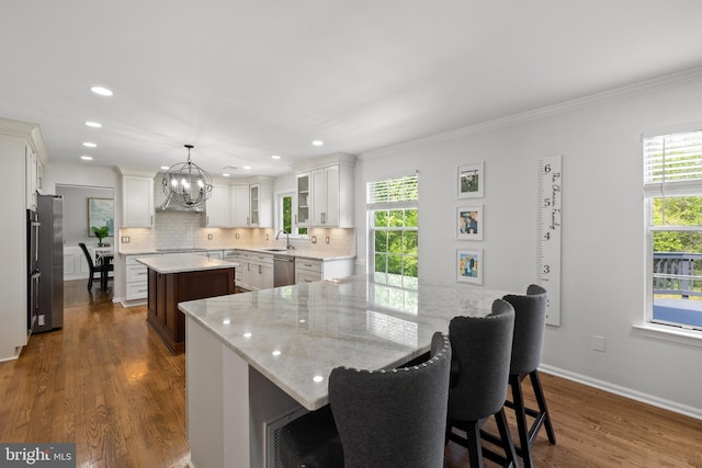 kitchen with backsplash, a kitchen island, appliances with stainless steel finishes, a chandelier, and dark wood-type flooring