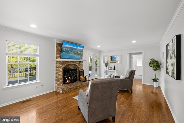 living area featuring visible vents, crown molding, a brick fireplace, and a wealth of natural light