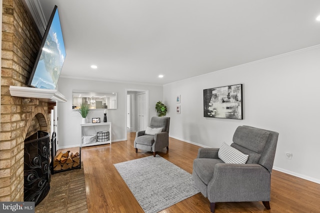 living area with a fireplace, recessed lighting, baseboards, wood finished floors, and ornamental molding