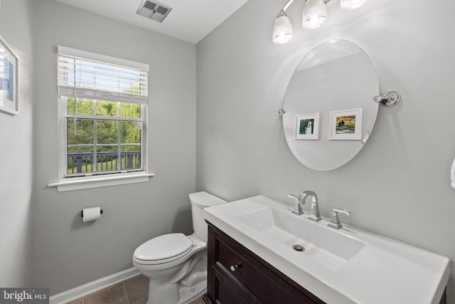 half bath with visible vents, vanity, toilet, baseboards, and tile patterned floors