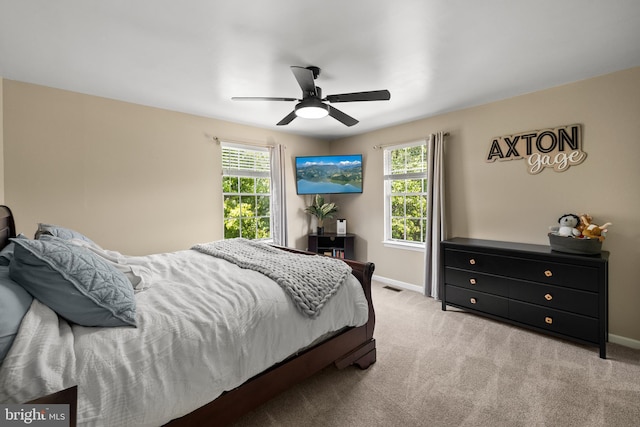 carpeted bedroom featuring baseboards, visible vents, multiple windows, and ceiling fan