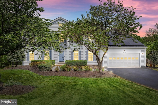 view of front of property with an attached garage, solar panels, a front lawn, and aphalt driveway