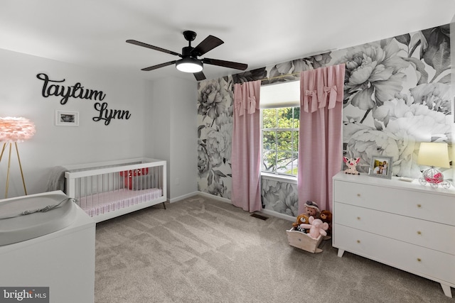 bedroom with a crib, carpet, a ceiling fan, and visible vents