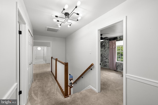 hallway with visible vents, an inviting chandelier, an upstairs landing, and light colored carpet