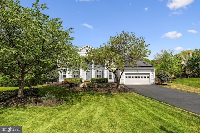 obstructed view of property featuring an attached garage, a front lawn, roof mounted solar panels, and driveway