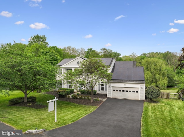 view of front of property with fence, a garage, a front yard, solar panels, and driveway