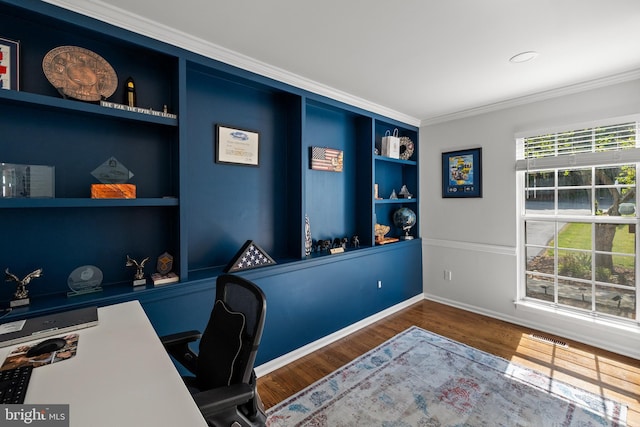 office area featuring visible vents, built in features, wood finished floors, baseboards, and ornamental molding