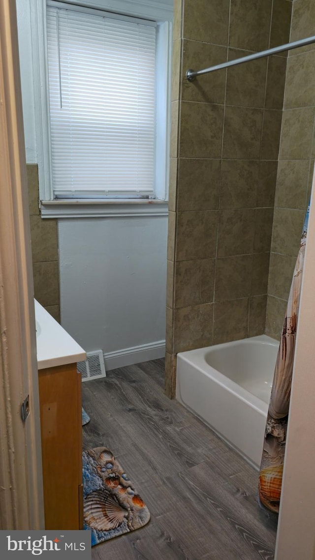 full bath featuring shower / bathtub combination with curtain, wood finished floors, visible vents, vanity, and baseboards