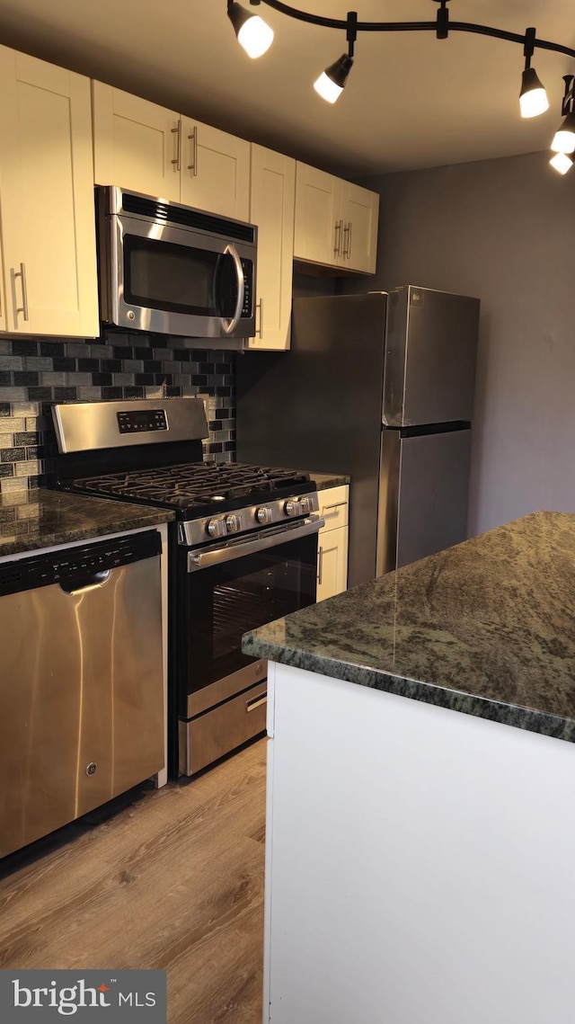 kitchen featuring light wood-type flooring, backsplash, white cabinetry, and appliances with stainless steel finishes