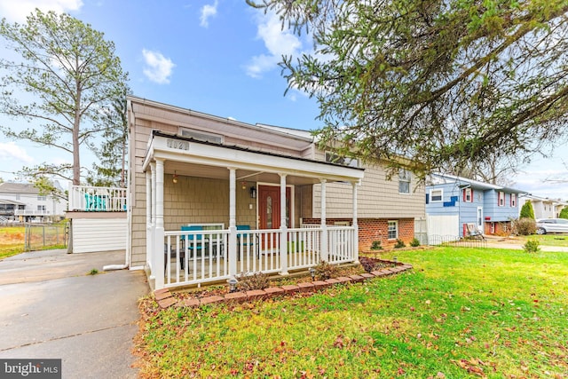 view of front of home with driveway, a porch, a front yard, and fence