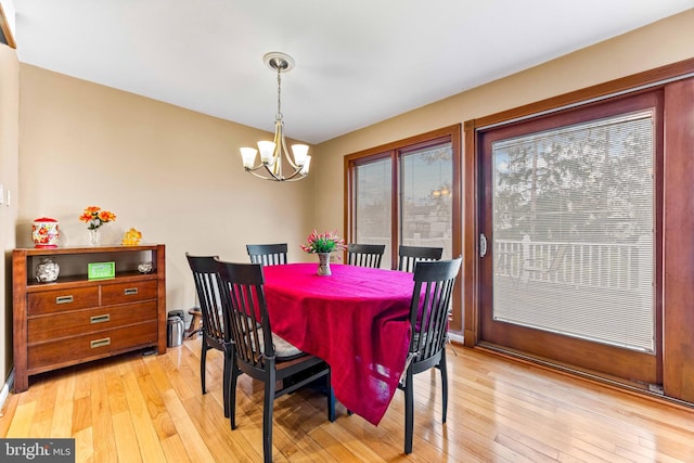 dining space featuring light wood-style floors and an inviting chandelier