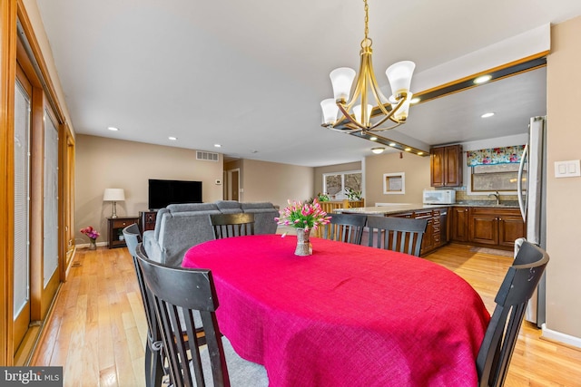 dining space with a notable chandelier, light wood finished floors, and visible vents