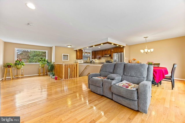 living room featuring baseboards, light wood-style floors, and a chandelier