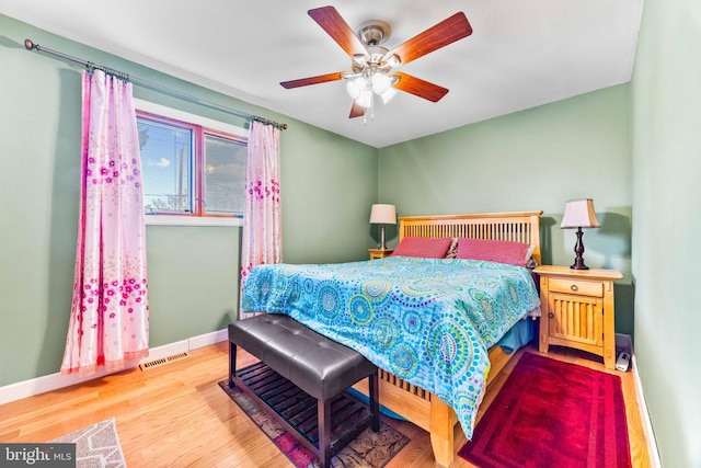 bedroom with visible vents, wood finished floors, baseboards, and ceiling fan