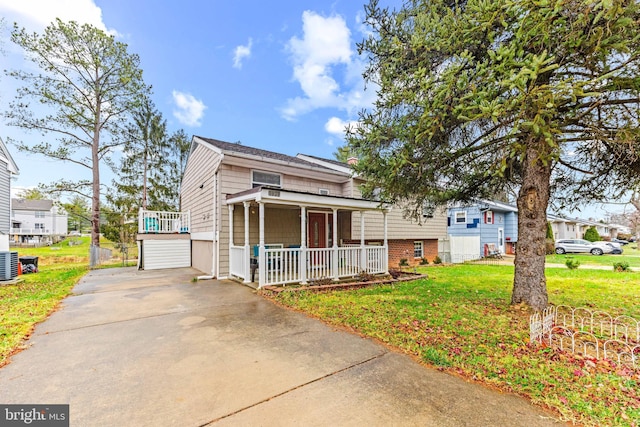 view of front facade with central air condition unit, driveway, a porch, and a front yard