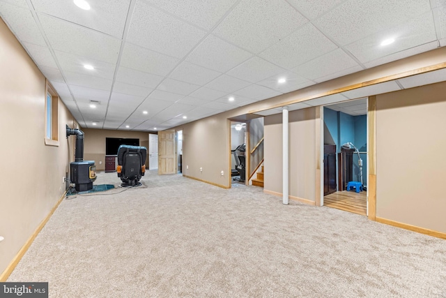 finished below grade area with baseboards, carpet, stairs, and a wood stove