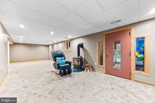 sitting room with carpet flooring, visible vents, baseboards, recessed lighting, and a wood stove