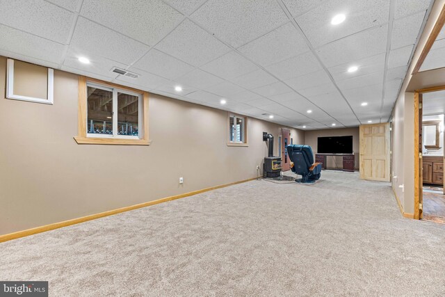 interior space featuring baseboards, visible vents, recessed lighting, carpet floors, and a wood stove