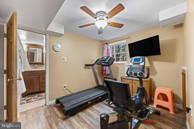 workout area with wood finished floors, a ceiling fan, baseboards, and a sink
