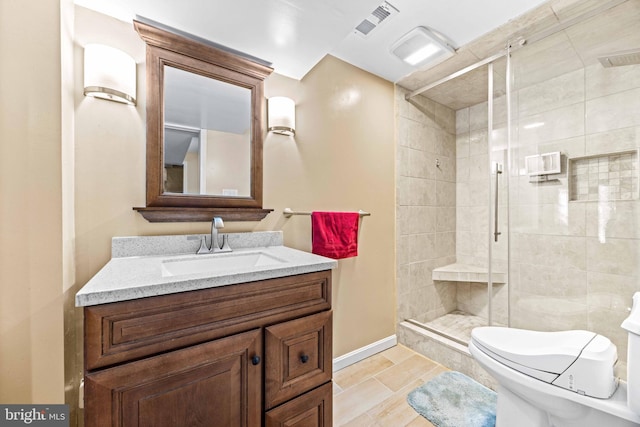 bathroom with a shower stall, vanity, baseboards, toilet, and visible vents