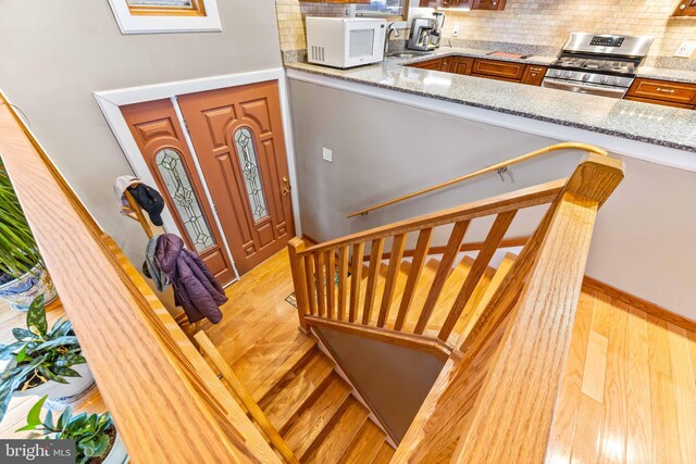 entryway featuring baseboards, light wood-style floors, and stairway