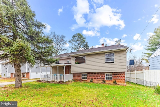 back of house with a yard, a porch, a chimney, and fence