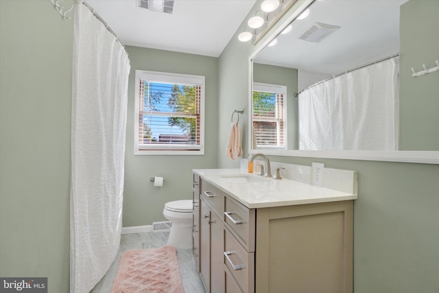 full bathroom with vanity, baseboards, toilet, and visible vents